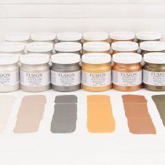 A bunch of jars of paint are lined up on a table.