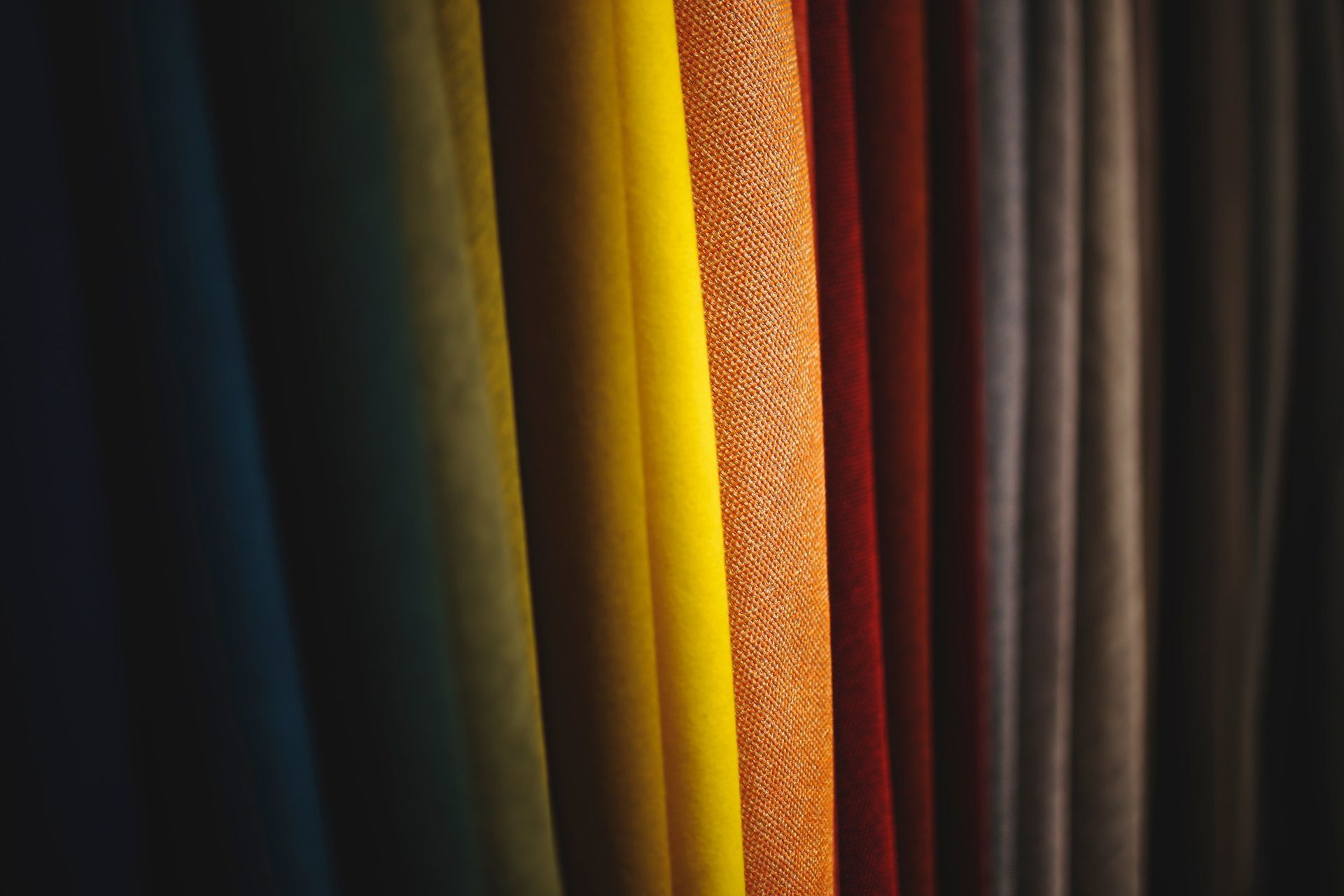 A close up of a row of colorful curtains hanging on a wall.