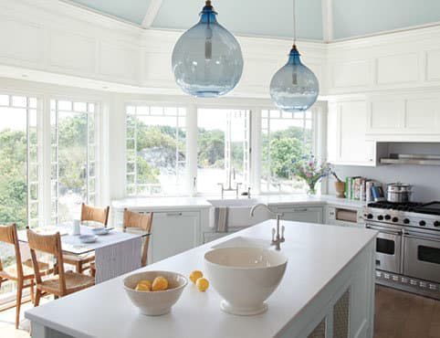 A kitchen with a large island, a stove, a sink, a table and chairs.